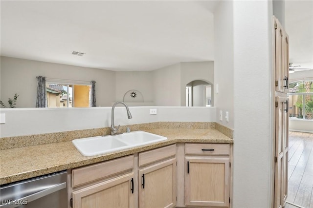 kitchen featuring visible vents, light brown cabinetry, a sink, stainless steel dishwasher, and light countertops