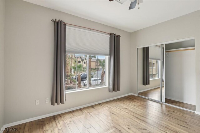 unfurnished bedroom with ceiling fan, a closet, baseboards, and wood finished floors