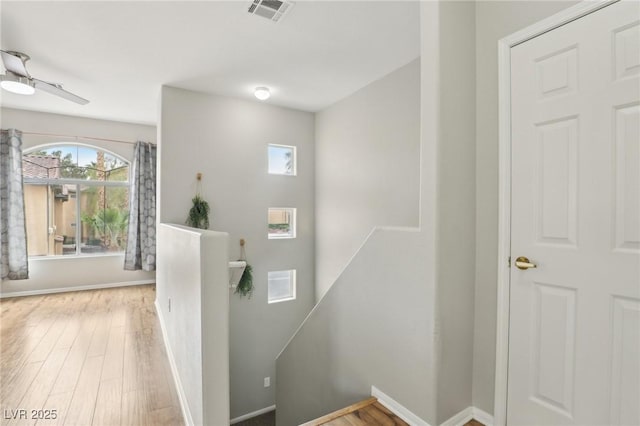 staircase with wood finished floors, visible vents, and baseboards