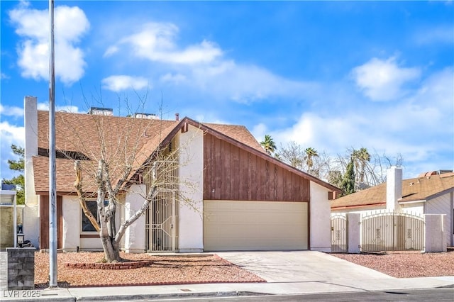 view of front of property featuring stucco siding, concrete driveway, an attached garage, and a gate