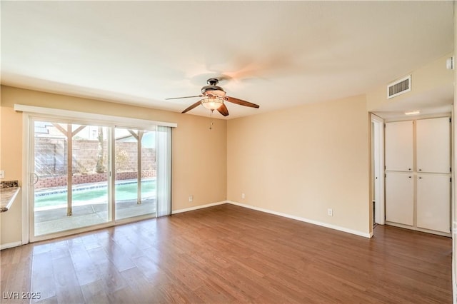 unfurnished room with visible vents, ceiling fan, baseboards, and wood finished floors