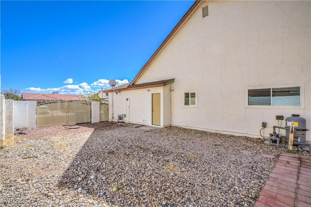 rear view of house with fence and stucco siding