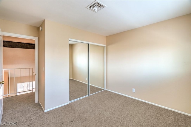 unfurnished bedroom with carpet, visible vents, a closet, and baseboards