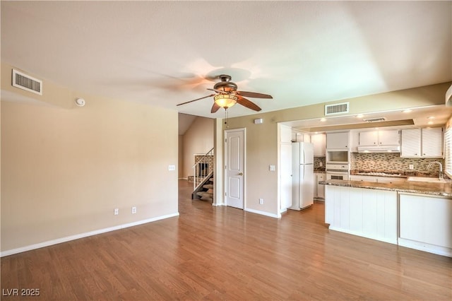 kitchen featuring visible vents, white appliances, backsplash, and a peninsula