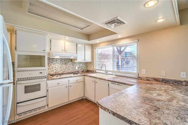 kitchen with a warming drawer, visible vents, a sink, under cabinet range hood, and white appliances