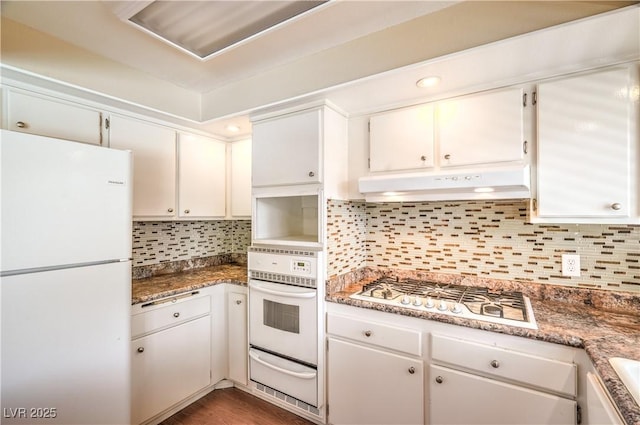 kitchen featuring white appliances, a warming drawer, backsplash, and under cabinet range hood