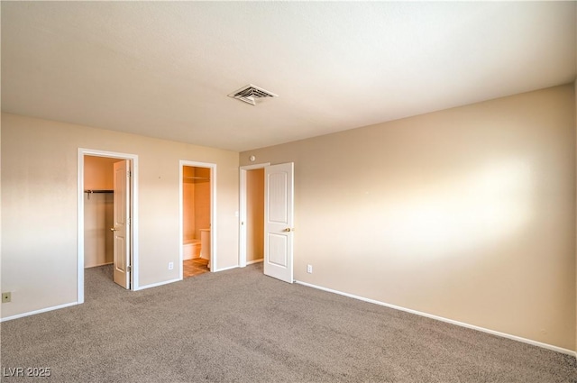 unfurnished bedroom featuring a spacious closet, visible vents, baseboards, carpet floors, and a closet