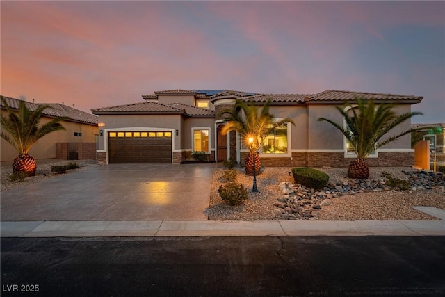 mediterranean / spanish home with stucco siding, an attached garage, stone siding, driveway, and a tiled roof