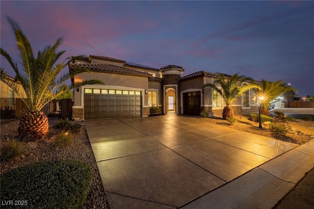 mediterranean / spanish-style home with an attached garage, solar panels, fence, driveway, and stucco siding