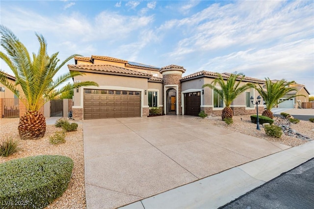 mediterranean / spanish-style house with an attached garage, fence, driveway, a gate, and stucco siding