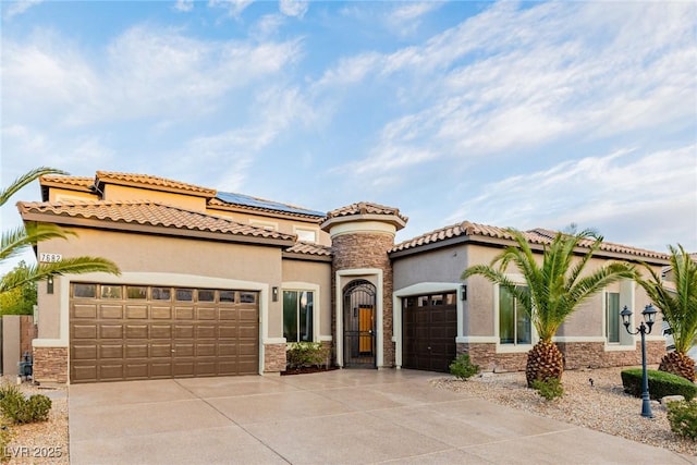 mediterranean / spanish-style home featuring an attached garage, stone siding, driveway, and stucco siding