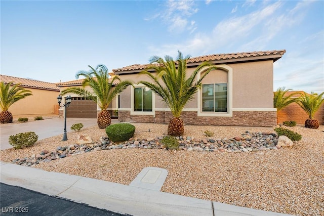 mediterranean / spanish home featuring stone siding, an attached garage, driveway, and stucco siding