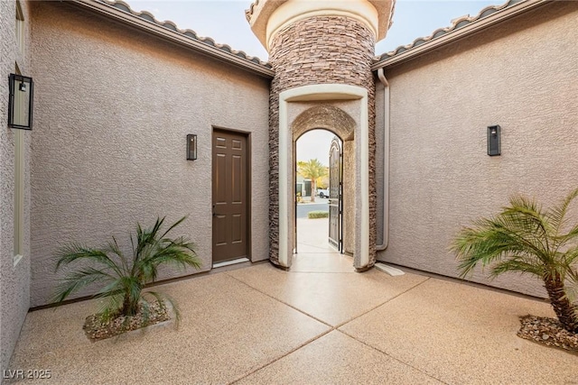 property entrance with stone siding, a tiled roof, and stucco siding