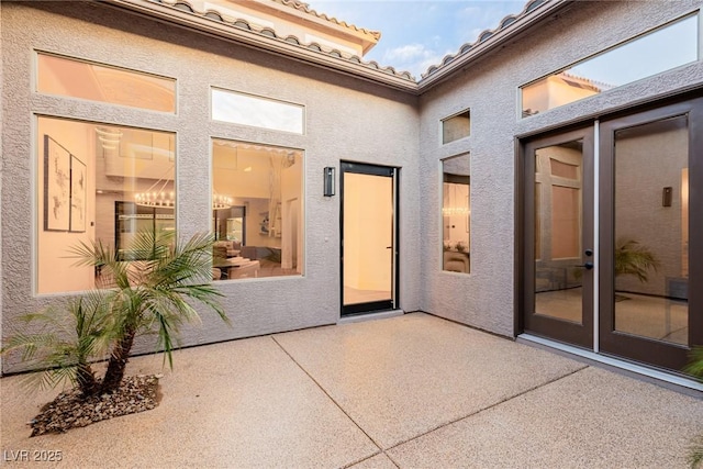 exterior space with a patio area, a tile roof, and stucco siding