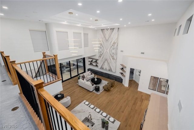 living room with a raised ceiling, wood finished floors, and recessed lighting