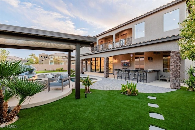 back of house featuring outdoor dry bar, a yard, and a patio area