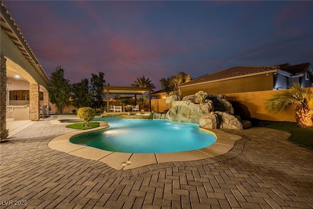 pool at dusk with an outdoor pool, a fenced backyard, and a patio