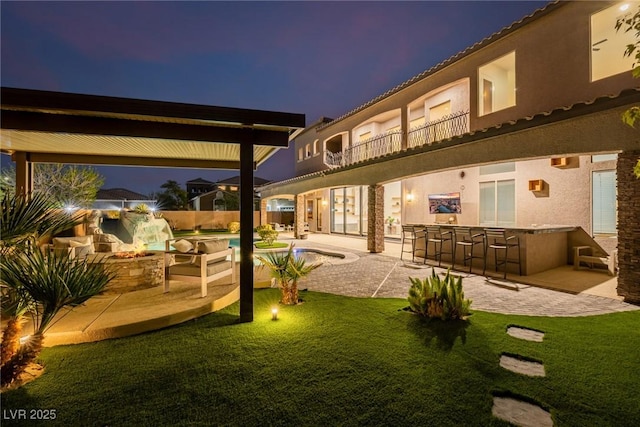 back of property with outdoor dry bar, stucco siding, a patio area, and an outdoor pool