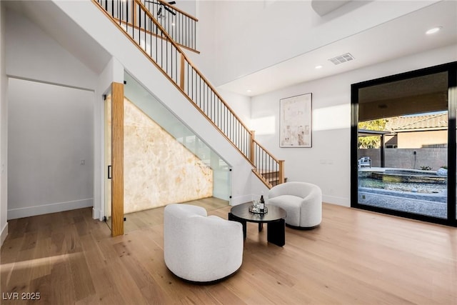 interior space featuring visible vents, stairway, a high ceiling, and wood finished floors