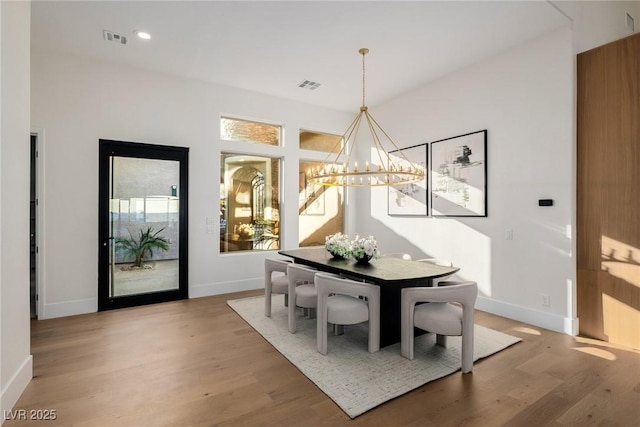 dining area featuring baseboards, wood finished floors, visible vents, and a notable chandelier