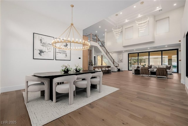 dining space with recessed lighting, a towering ceiling, baseboards, and wood finished floors