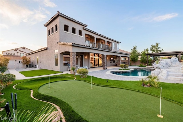 rear view of house featuring a fenced in pool, stucco siding, a patio area, a balcony, and cooling unit