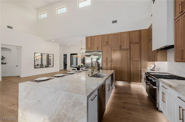 kitchen with premium appliances, a spacious island, visible vents, and light wood-style floors