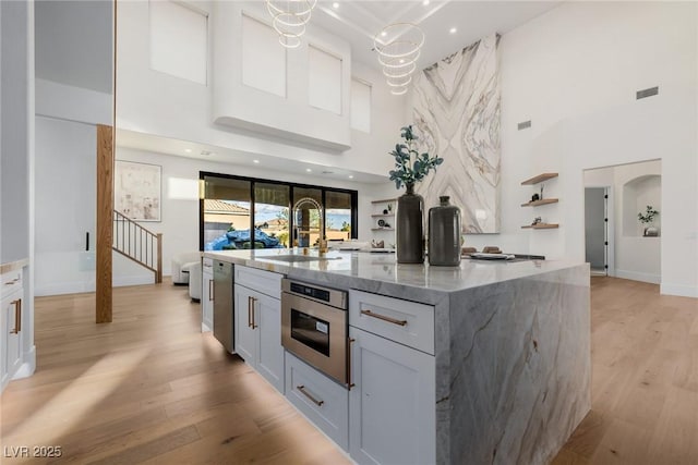 kitchen featuring arched walkways, a sink, visible vents, light wood-style floors, and open shelves