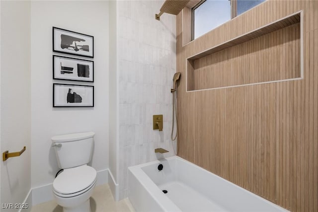 bathroom featuring toilet, baseboards, and tub / shower combination