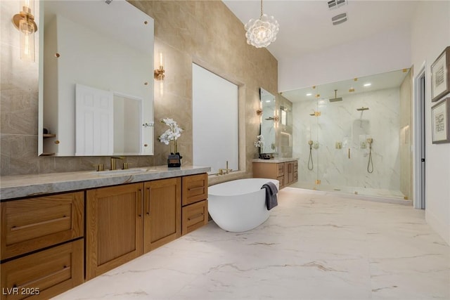 bathroom with marble finish floor, a marble finish shower, a soaking tub, two vanities, and a sink