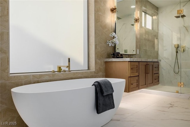 full bath with a marble finish shower, marble finish floor, a freestanding bath, vanity, and tile walls