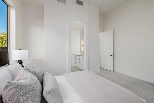 bedroom with light carpet, connected bathroom, visible vents, and baseboards