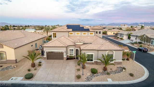 mediterranean / spanish home featuring concrete driveway, a tile roof, a residential view, an attached garage, and stucco siding