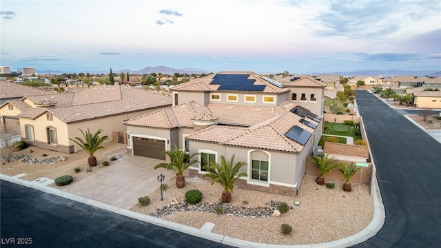 mediterranean / spanish-style home with concrete driveway, a residential view, a tiled roof, roof mounted solar panels, and stucco siding