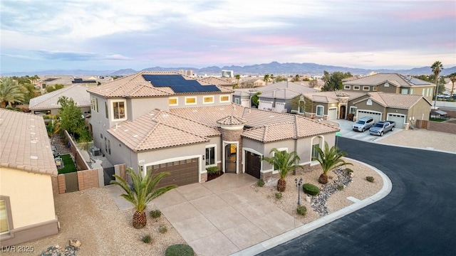 mediterranean / spanish-style home with concrete driveway, a tile roof, a residential view, an attached garage, and a gate