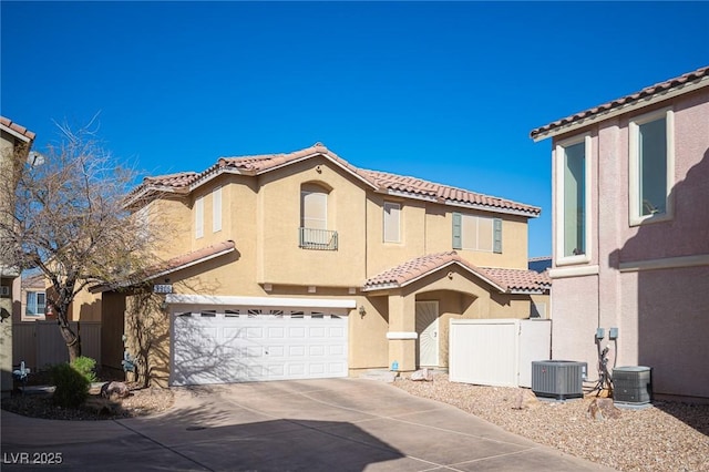 mediterranean / spanish-style house featuring a tile roof, stucco siding, concrete driveway, fence, and a garage