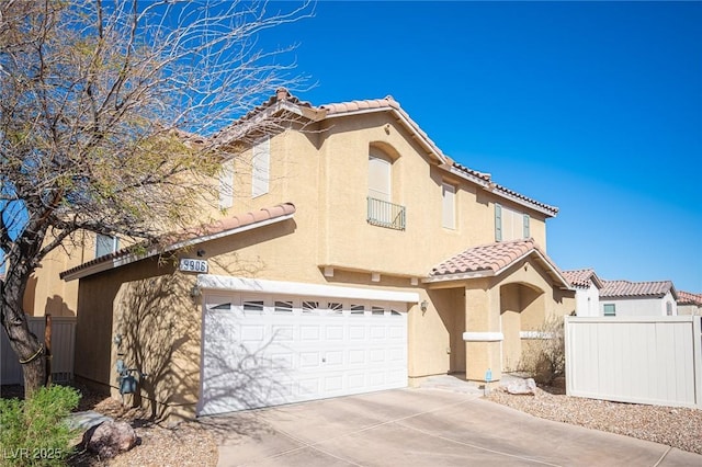 mediterranean / spanish home featuring stucco siding, concrete driveway, fence, a garage, and a tiled roof