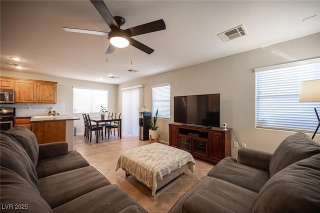 living area with light tile patterned flooring, visible vents, and a healthy amount of sunlight