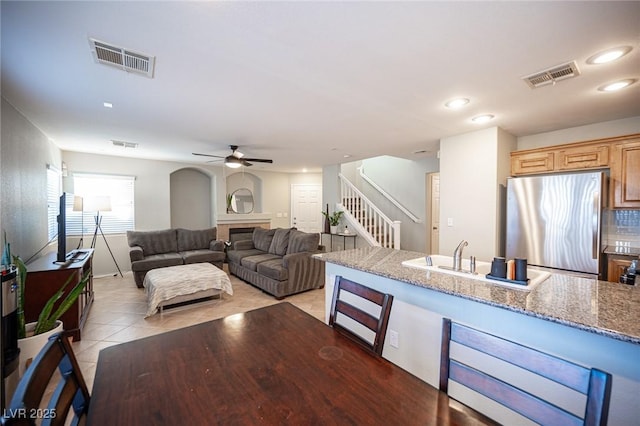 living room featuring light tile patterned floors, stairs, a fireplace, and visible vents