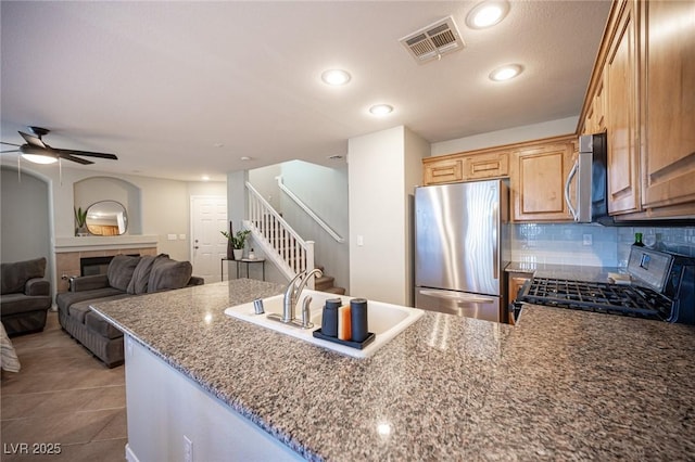 kitchen featuring visible vents, a tiled fireplace, appliances with stainless steel finishes, a peninsula, and backsplash