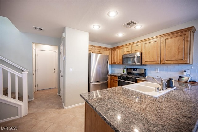 kitchen with visible vents, decorative backsplash, appliances with stainless steel finishes, dark stone countertops, and a sink