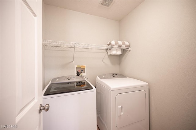 washroom with laundry area, separate washer and dryer, and visible vents