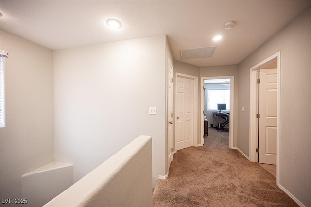 corridor with carpet floors, visible vents, and baseboards