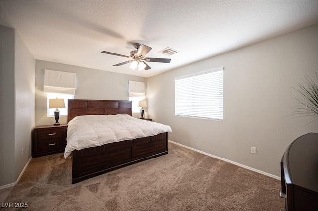 carpeted bedroom featuring baseboards, a textured ceiling, visible vents, and a ceiling fan