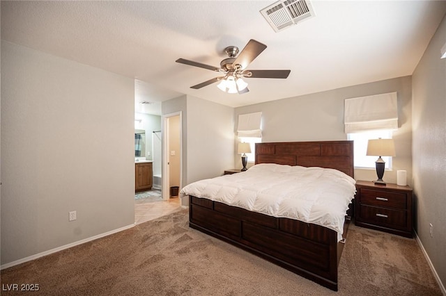 bedroom featuring visible vents, light carpet, ceiling fan, ensuite bath, and baseboards