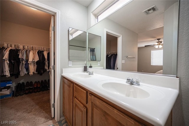 bathroom featuring double vanity, visible vents, a walk in closet, and a sink