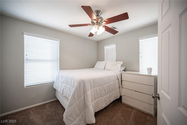 bedroom featuring ceiling fan, multiple windows, visible vents, and dark colored carpet