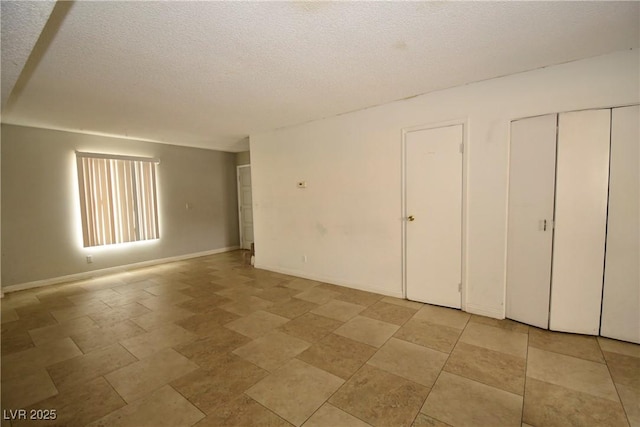 unfurnished bedroom featuring a textured ceiling, a closet, and baseboards