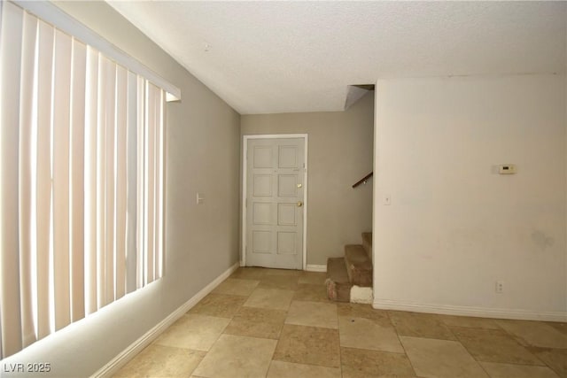 basement featuring stairs, baseboards, and a textured ceiling