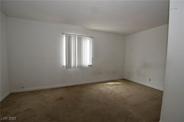 empty room with carpet floors, a textured ceiling, and baseboards